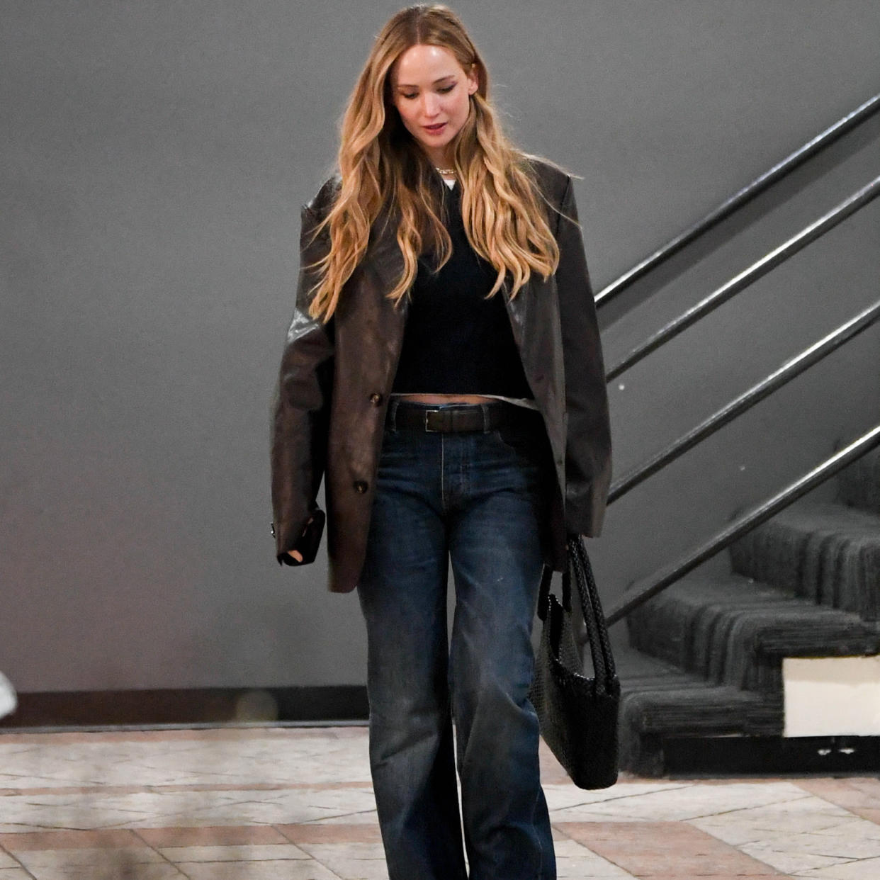  Jennifer Lawrence wearing a brown blazer with a black top and blue jeans . 