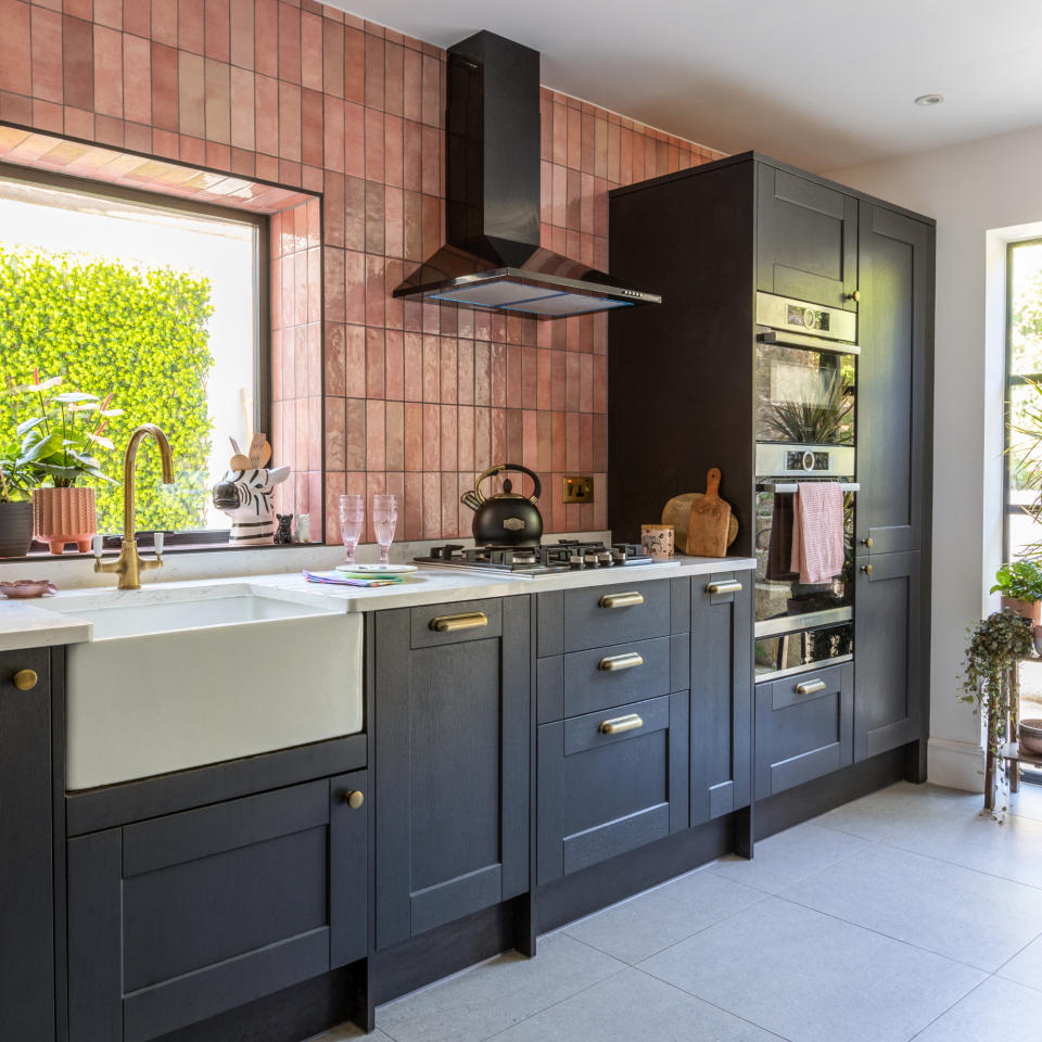 Black kitchen with grey feature wall, window, cabinets and countertop