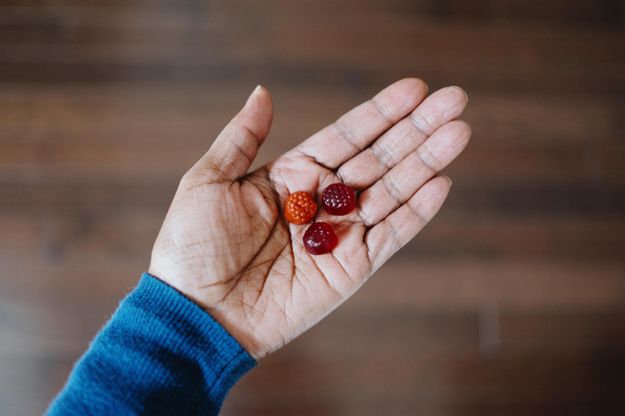 High angle view of woman's hand holding fruit-flavored gummy nutritional supplements