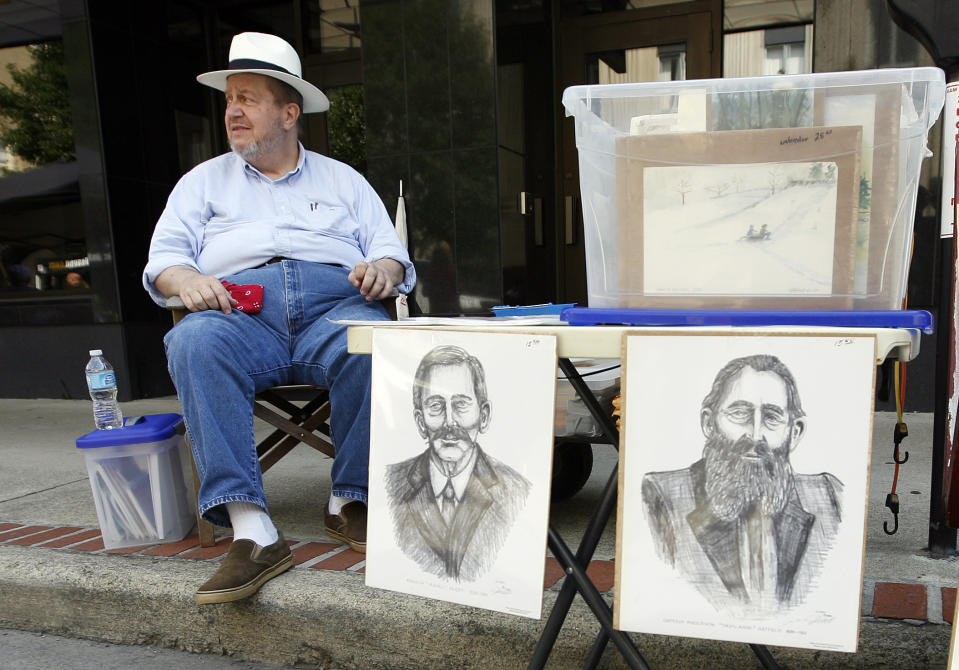 In a Saturday, June 9, 2012 photo, regional artist J.D. Hall sells his artwork which includes prints of Randolph McCoy, left, and Devil Anse Hatfield during the Hatfield-McCoy Reunion in Williamson, W.V. (AP Photo/ James Crisp)