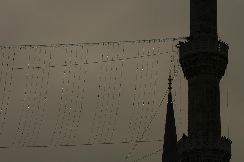 Mahya masters work in the installation of a lights message at the top of one of the minarets of the Suleymaniye mosque ahead of the Muslim holy month of Ramadan in Istanbul, Turkey, Tuesday, March 5, 2024. Mahya is the unique Turkish tradition of stringing religious messages and designs between minarets. (AP Photo/Emrah Gurel)