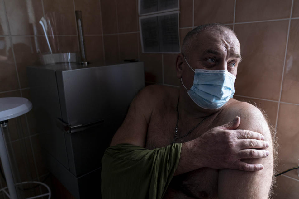 A Ukrainian serviceman gets ready to receive a dose of the AstraZeneca COVID-19 vaccine marketed under the name CoviShield at a military base in Kramatorsk, Ukraine, Tuesday, March 2, 2021. Ukraine plans to vaccinate 14.4 million people this year, or about 35% of its 41 million people. (AP Photo/Evgeniy Maloletka)