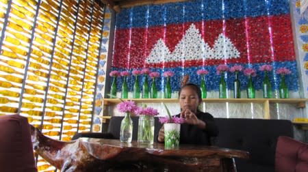 A girl prepares vases with flowers at the Rubbish Cafe, a coffee shop made of rubbish, at the Kirirom National Park in Kampong Speu province, Cambodia