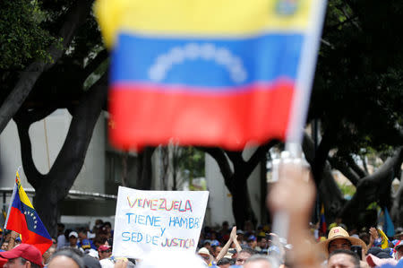 Demonstrators hold Venezuelan flag and a sign reads: 'Venezuela is hungry and has thirst for justice' while rallying against Venezuela's President Nicolas Maduro in Caracas, Venezuela May 1, 2017. REUTERS/Carlos Garcia Rawlins
