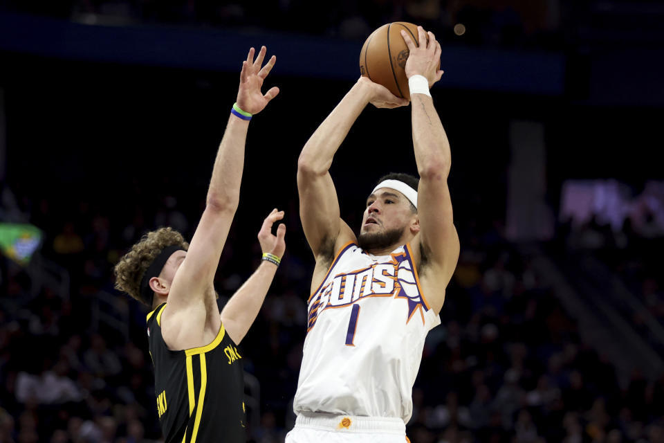 Phoenix Suns guard Devin Booker (1) shoots against Golden State Warriors guard Brandin Podziemski, left, during the first half of an NBA basketball game in San Francisco, Saturday, Feb. 10, 2024. (AP Photo/Jed Jacobsohn)