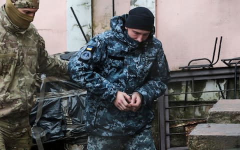 A Russian FSB security service officer escorts a detained Ukrainian sailor to a courthouse in Simferopol, Crimea - Credit: STR/AFP/Getty Images