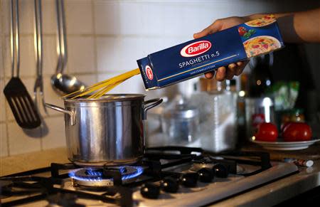 A man throws Barilla spaghetti into boiling water as he cooks at his home in Rome September 27, 2013. REUTERS/Max Rossi