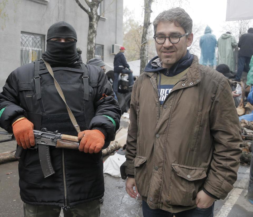 In this photo taken on Sunday, April 13, 2014, a reporter Simon Ostrovsky, right, stands next to a Pro-Russian gunman at a seized police station in the eastern Ukraine town of Slovyansk. Pro-Russian gunmen in eastern Ukraine say they are holding an American journalist captive. Ostrovsky, a journalist for Vice News, has not been seen since early Tuesday. (AP Photo/Efrem Lukatsky)