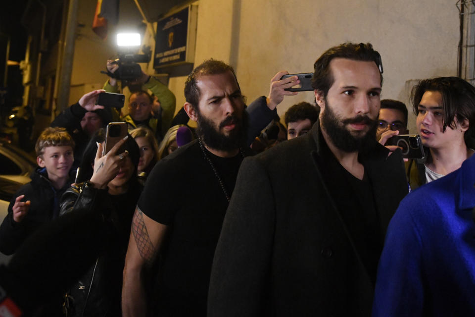 Young fans and media surround Andrew Tate, left, and his brother Tristan as they leave a police detention facility in Bucharest, Romania, after his release from prison on Friday March 31, 2023. An official on Friday said Tate, the divisive internet personality who has spent months in a Romanian jail on suspicion of organized crime and human trafficking, has won an appeal to replace his detention with house arrest. (AP Photo/Alexandru Dobre)