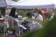 A "promotora" (health promoter) from CASA, a Hispanic advocacy group, tries to enroll Latinos as volunteers to test a potential COVID-19 vaccine, at a farmers market in Takoma Park, Md., on Sept. 9, 2020. Minority enrollment in studies of two shots has inched up in recent weeks, but even more is needed this fall as additional vaccine testing gets underway over the next two months. (AP Photo/Federica Narancio)