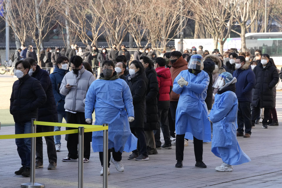 Medical workers stand to guide people as they wait for their coronavirus test at a makeshift testing site in Seoul, South Korea, Friday, Feb. 18, 2022. (AP Photo/Ahn Young-joon)