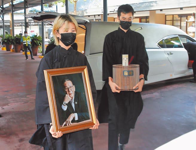 龍劭華兒子陳威佐（右）手捧父親牌位，女兒陳璇捧著遺照。（粘耿豪攝）