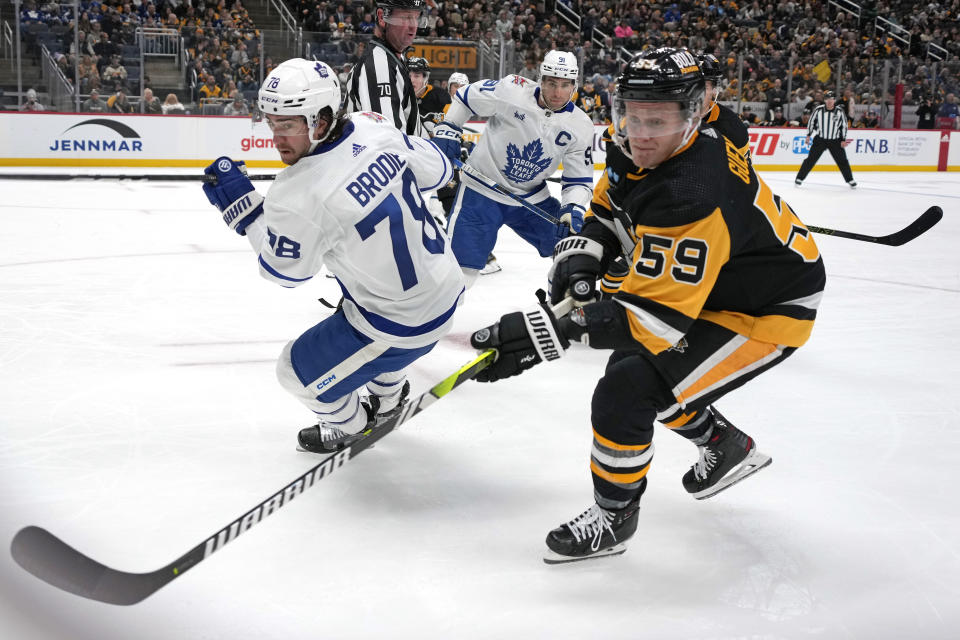 Pittsburgh Penguins' Jake Guentzel (59) and Toronto Maple Leafs' TJ Brodie (78) chase the puck into the corner during the second period of an NHL hockey game in Pittsburgh, Saturday, Nov. 25, 2023. (AP Photo/Gene J. Puskar)