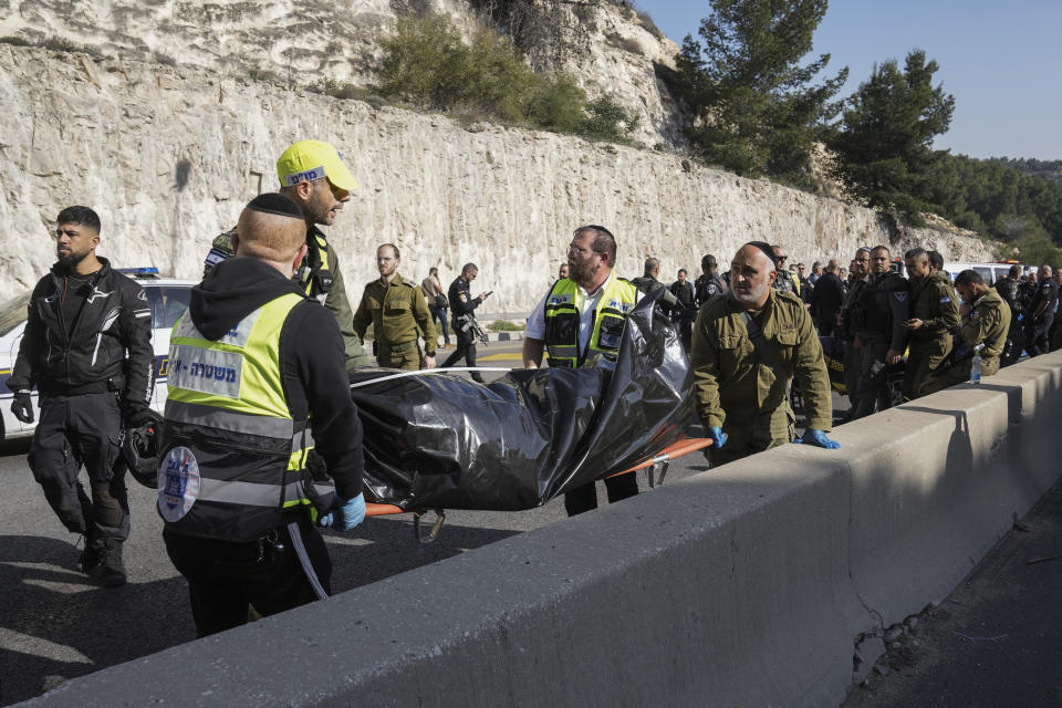 Israeli security forces and members of Zaka rescue service carry a body from the scene of a shooting attack near the West Bank settlement of Maale Adumim, Thursday, Feb. 22, 2024. Israel police said three Palestinian gunmen opened fire on the road near the settlement, killing one and wounding at least eight; security forces on the site killed two of the gunmen, and a third was found during searches of the area afterwards and was detained. (AP Photo/Mahmoud Illean)