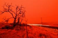 A long exposure picture shows a car commuting on a road as the sky turns red because of smoke from the Snowy Valley bushfire on the outskirts of Cooma, in Australia's New South Wales state