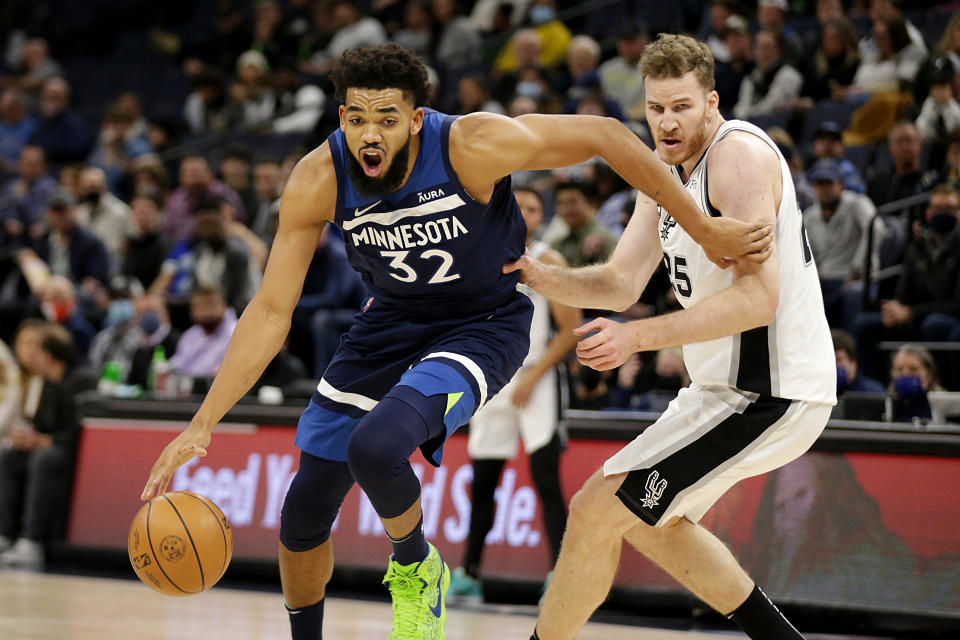 Minnesota Timberwolves center Karl-Anthony Towns (32) drives against San Antonio Spurs center Jakob Poeltl (25) in the first half of an NBA basketball game, Thursday, Nov. 18, 2021, in Minneapolis. (AP Photo/Andy Clayton-King)