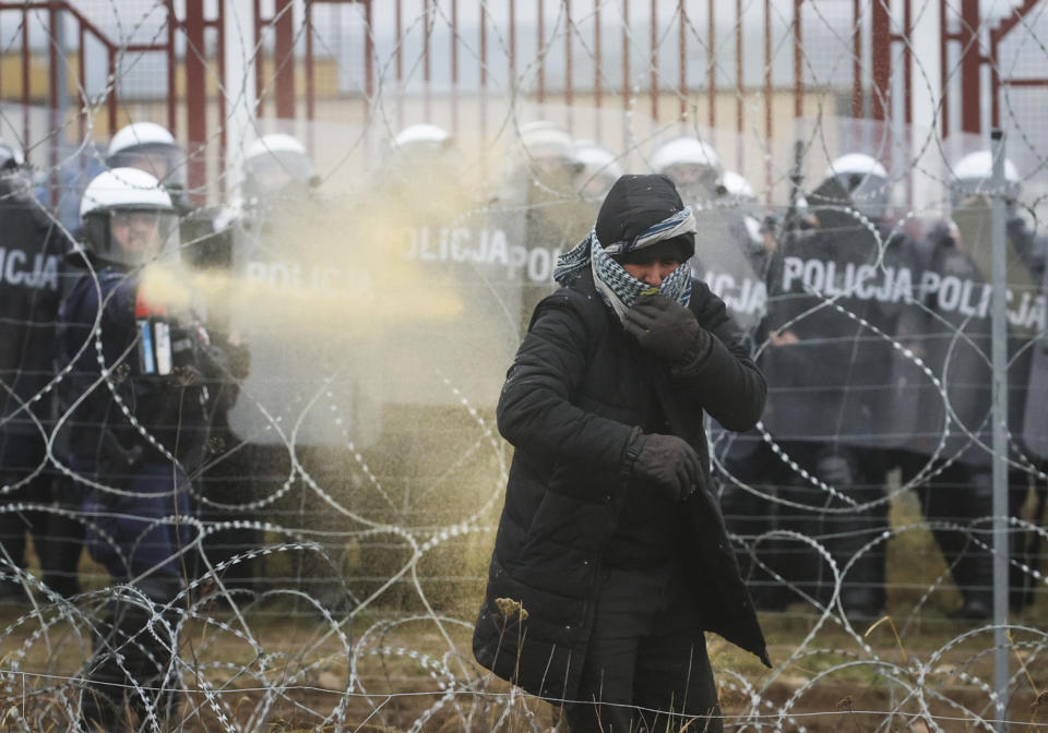 Polish serviceman sprays tear gas during clashes between migrants and Polish border guards at the Belarus-Poland border near Grodno, Belarus, on Tuesday, Nov. 16, 2021. Polish border forces say they were attacked with stones by migrants at the border with Belarus and responded with a water cannon. The Border Guard agency posted video on Twitter showing the water cannon being directed across the border at a group of migrants in a makeshift camp. (Leonid Shcheglov/BelTA via AP)