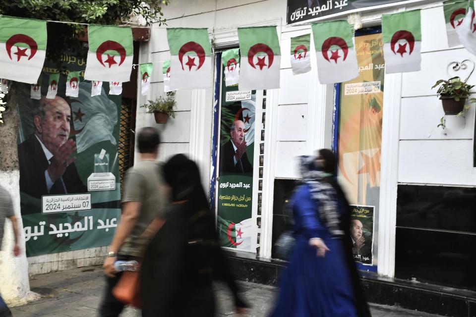 People walk past posters of Algerian President Abdelmadjid Tebboune, after the presidential elections results were announced and Tebboune being declared the winner of Algeria's election, Sunday, Sept. 8, 2024, in the capital Algiers. (AP Photo/Fateh Guidoum)