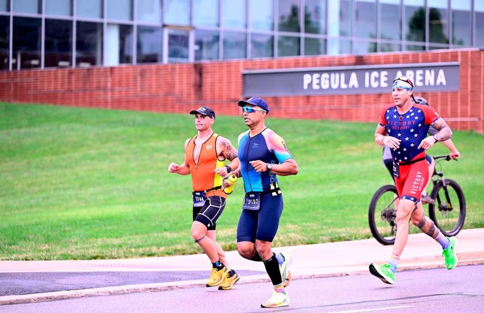 Participants in the Ironman 70.3 Pennsylvania Happy Valley triathlon run past Pegula Ice Arena on the University Park campus Sunday.