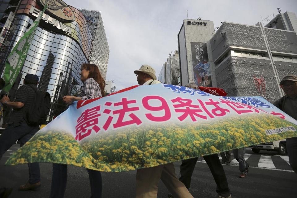 Hundreds of people march vowing to protect the constitution at Ginza shopping district in Tokyo, Saturday, May 3, 2014. Japan marked the 67th anniversary of its postwar constitution Saturday with growing debate over whether to revise the war-renouncing charter in line with Prime Minister Shinzo Abe's push for an expanded role for the military. The banner reads: "Article 9 of the Constitution is a treasure of the world." (AP Photo/Eugene Hoshiko)