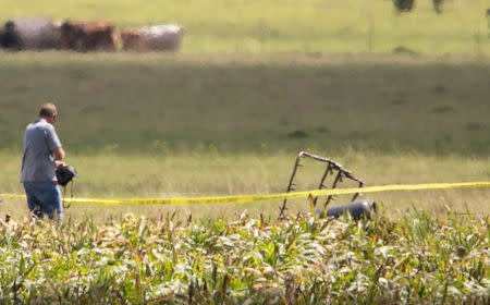 The partial frame of a hot air balloon is visible above a crop field as investigators comb the wreckage of a Saturday morning accident that left 16 people feared dead when the balloon crashed in Maxwell, Texas, U.S. July 30, 2016. Ralph Barrera/Austin American-Statesman/via REUTERS