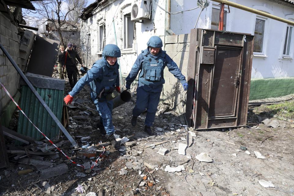 Emergency workers carry a fragment of a missile after shelling in a street in Donetsk, in territory under the government of the Donetsk People's Republic, in eastern Ukraine, Tuesday, April 5, 2022. (AP Photo/Alexei Alexandrov)