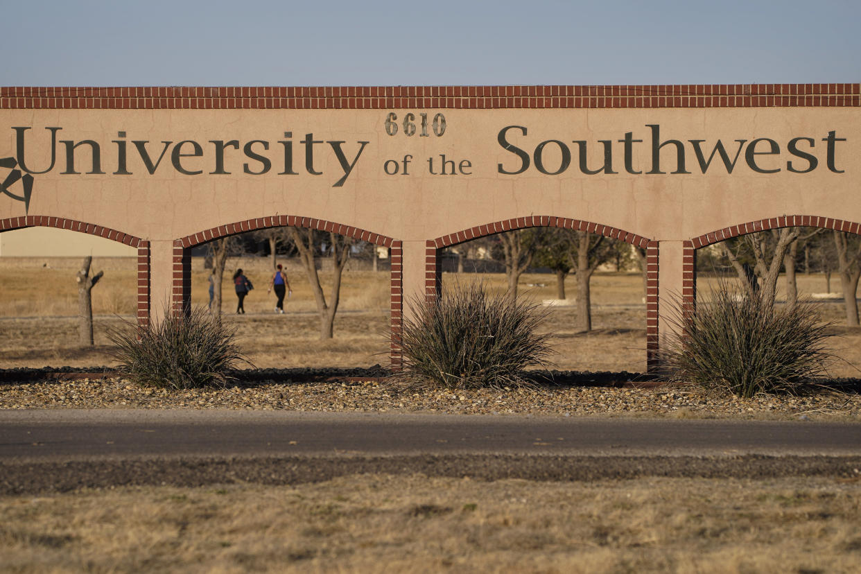 People walk through campus at the University of the Southwest, Wednesday, March 16, 2022, in Hobbs, N.M. Students and a golf coach from the school were killed in a head-on collision in West Texas on Tuesday. (AP Photo/John Locher)