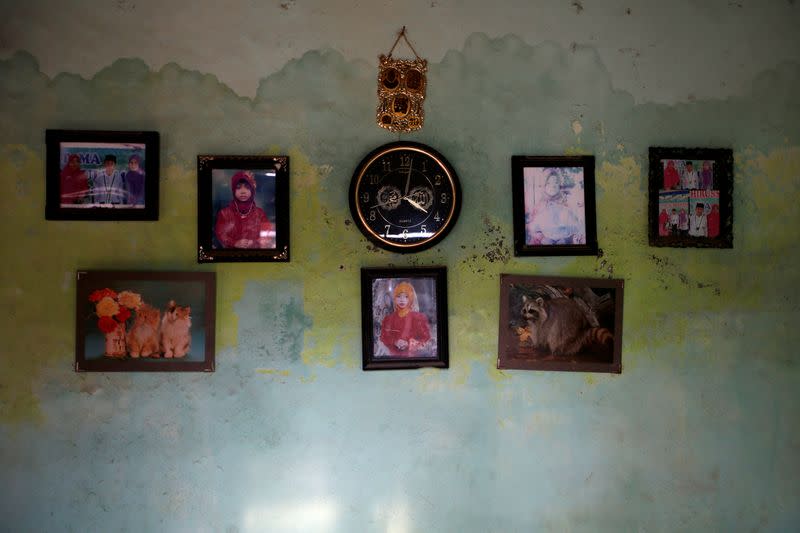 Photographs and a clock hang on a damp wall of fisherman Miskan's house at Tambaklorok, a village affected by land subsidence rising sea level, in Semarang