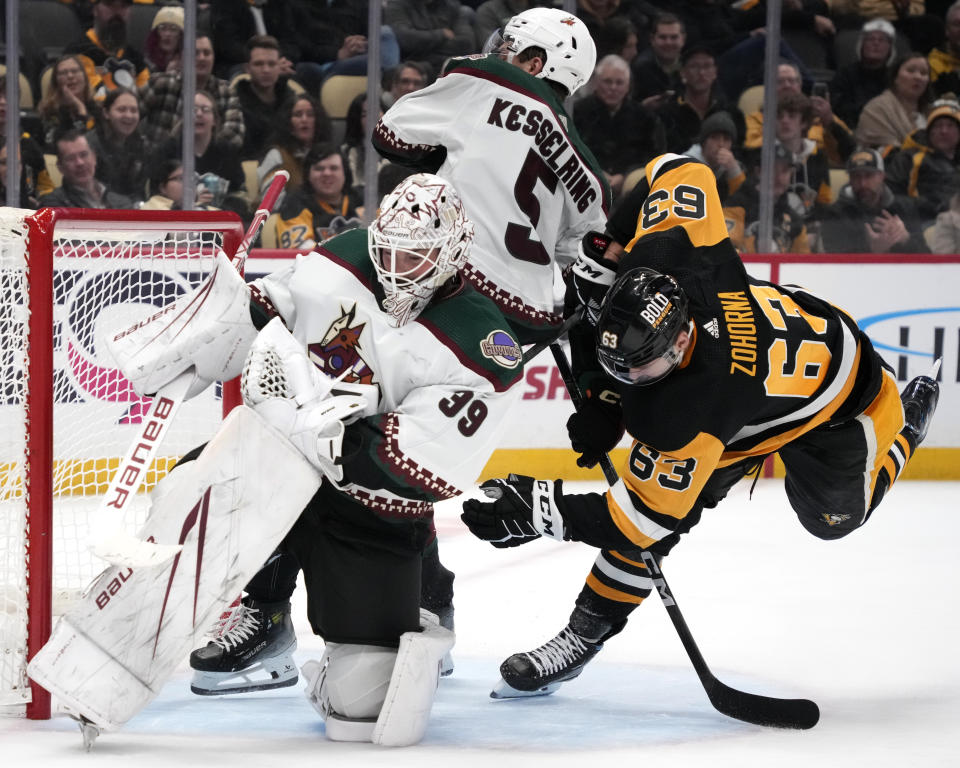 Arizona Coyotes goaltender Connor Ingram (39) makes a glove save on a shot by Pittsburgh Penguins' Radim Zohorna (63) as Michael Kesselring (5) defends during the second period of an NHL hockey game in Pittsburgh, Tuesday, Dec. 12, 2023. (AP Photo/Gene J. Puskar)