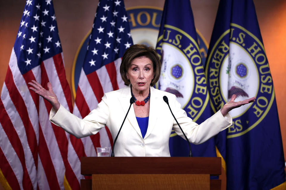 Nancy Pelosi stands at podium with arms extended