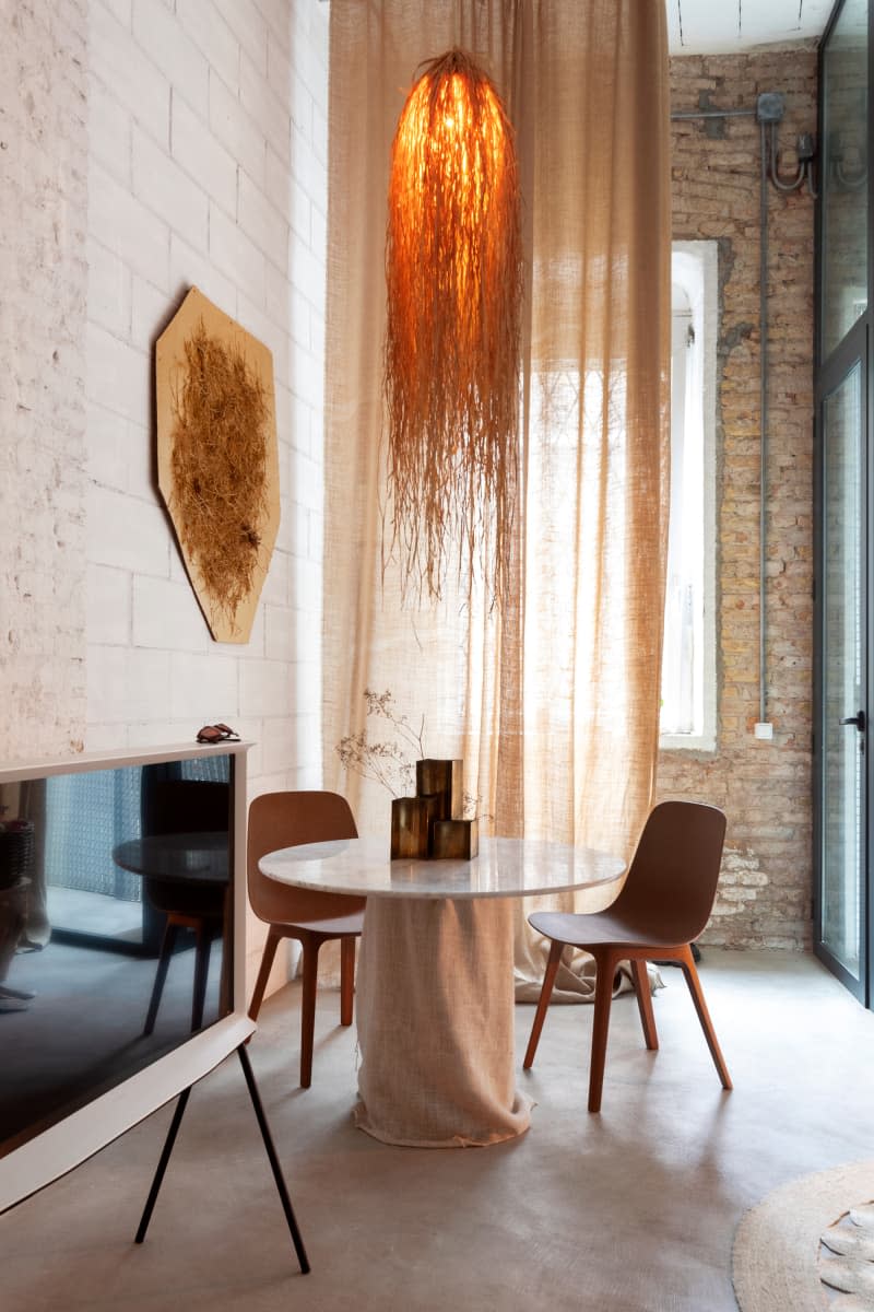 Dining room with white brick and exposed brick walls, large window, high ceilings, and stone floor