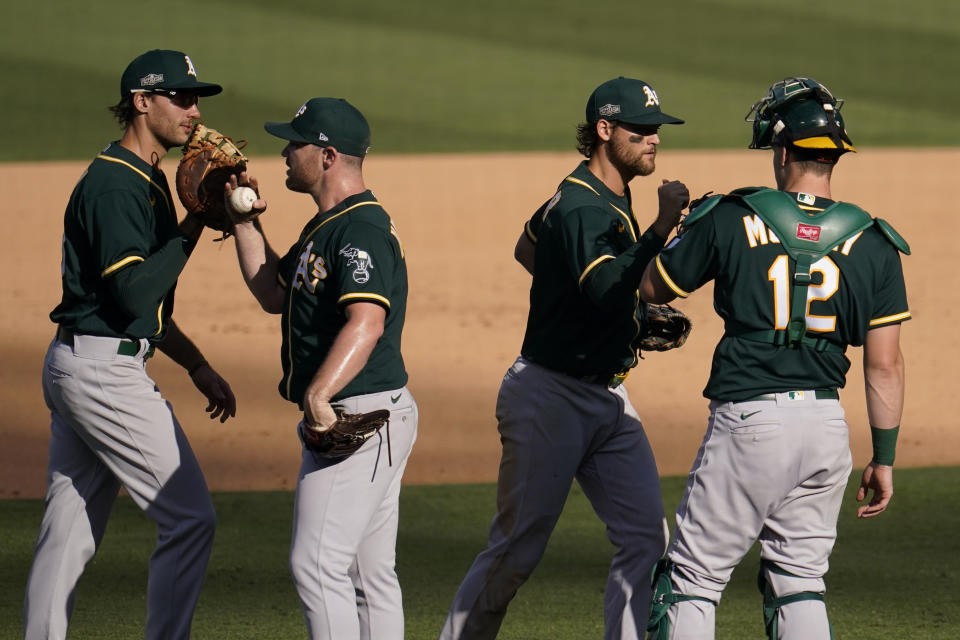 Oakland Athletics' Matt Olson, from left, celebrates with Liam Hendriks, Chad Pinder, and Sean Murphy after the Athletics defeated the Houston Astros in Game 3 of a baseball American League Division Series in Los Angeles, Wednesday, Oct. 7, 2020. (AP Photo/Marcio Jose Sanchez)