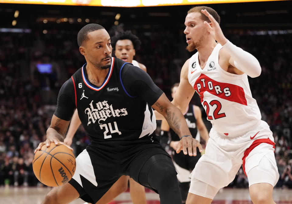 Los Angeles Clippers forward Norman Powell (24) protects the ball from Toronto Raptors guard Malachi Flynn (22) during the first half of an NBA basketball game Tuesday, Dec. 27, 2022, in Toronto. (Frank Gunn/The Canadian Press via AP)