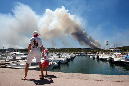 A woman and her daughter look at a plume of smoke from burning fires that fills the sky in Bormes-les-Mimosas, in the Var department, France, July 26, 2017. REUTERS/Jean-Paul Pelissier