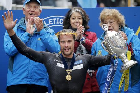 Marcel Hug of Switzerland holds up the trophy after winning the men's wheelchair division of the 119th Boston Marathon in Boston, Massachusetts April 20, 2015. REUTERS/Brian Snyder