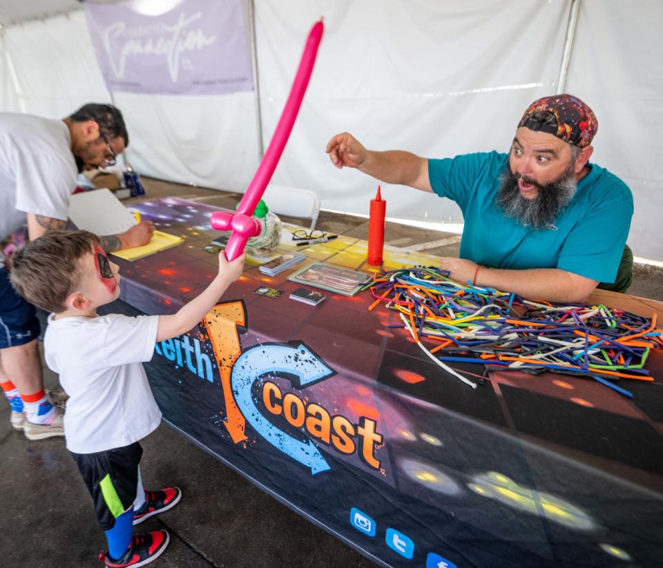 Magician and balloon artist Keith Coast entertains children at his booth during the Downtown Edmond Arts Festival.
