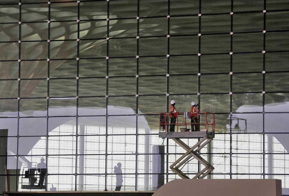 In this Wednesday, Jan. 8, 2014 photo, workers put final touches on a glass wall at the new airport terminal at the Chhatrapati Shivaji International Airport in Mumbai, India. India's overcrowded financial capital unveils its long-awaited $2 billion new airport terminal Friday, an ambitious, art-filled space that developers hope will be a showcase success in a country struggling to modernize inadequate infrastructure that is holding back economic growth. (AP Photo/Rajanish Kakade)