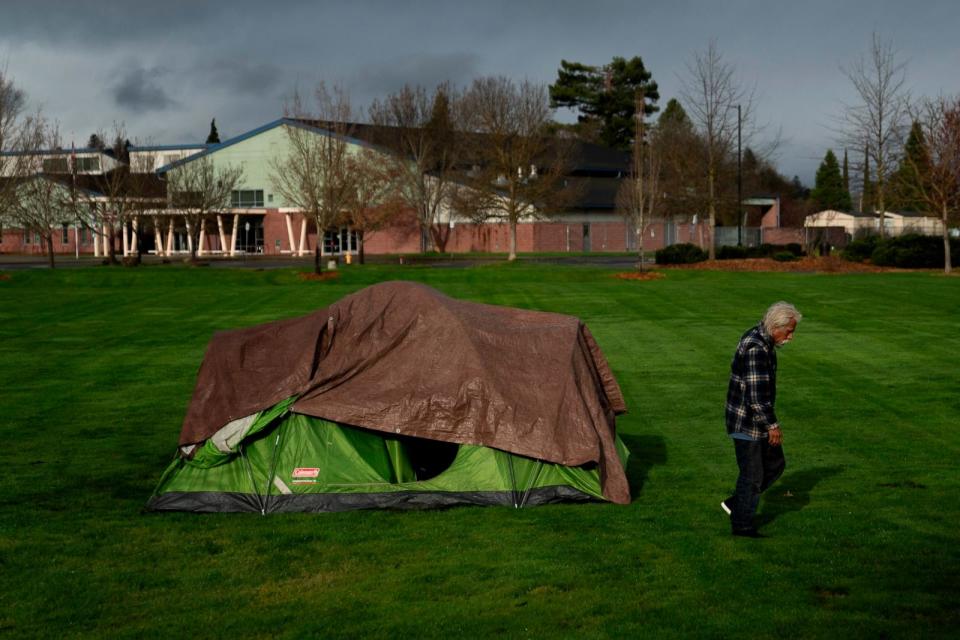 PHOTO: With Fruitdale Elementary School in the background, a homeless person walks near a tent in Fruitdale Park, March 23, 2024, in Grants Pass, Ore. (Jenny Kane/AP, FILE)