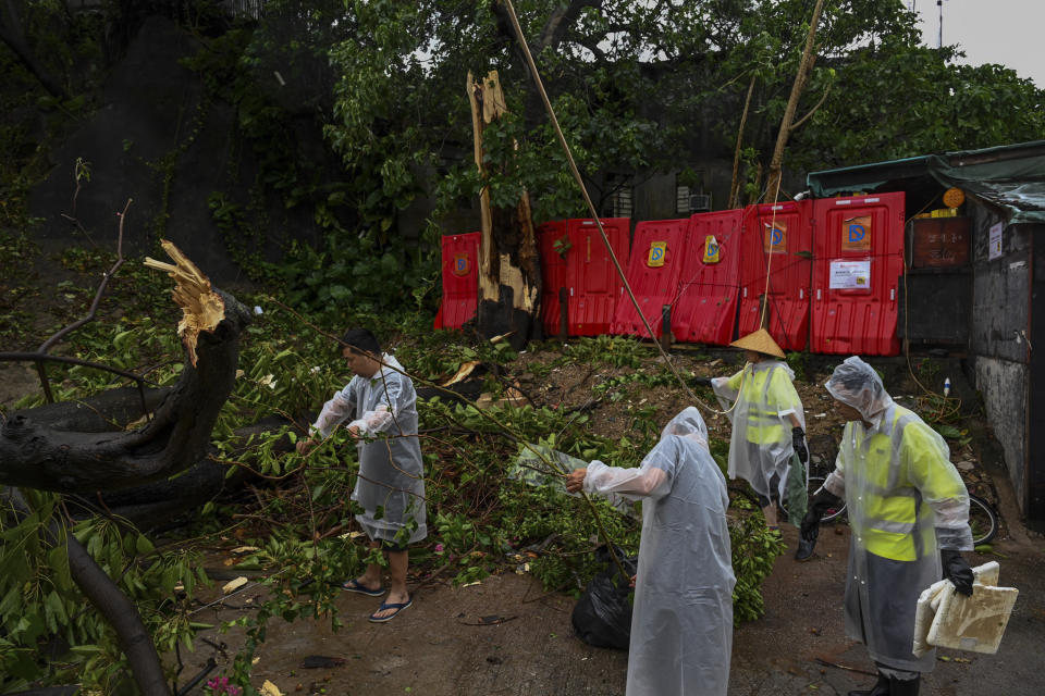 People clear debris near houses after Typhoon Saola struck the city with strong winds and rain, in Hong Kong, Saturday, Sept. 2, 2023. The typhoon made landfall in southern China before dawn Saturday after nearly 900,000 people were moved to safety and most of Hong Kong and other parts of coastal southern China suspended business, transport and classes. (AP Photo/Billy H.C. Kwok)