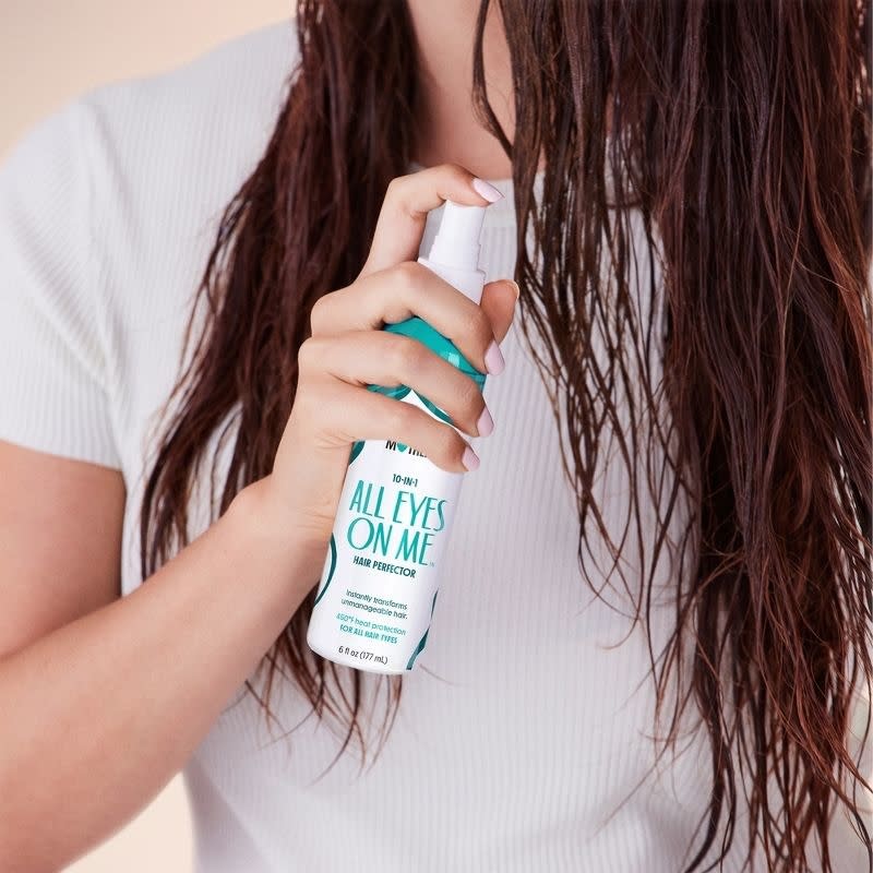 Model applying the spray to their hair