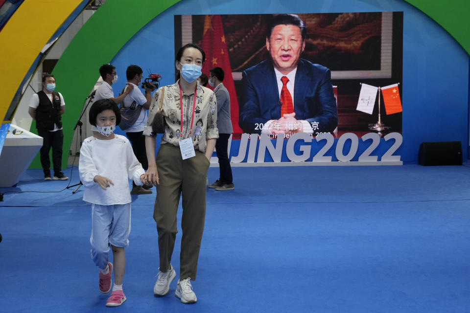 A woman and child wearing masks pass by a screen displaying Chinese President Xi Jinping during the China International Fair for Trade in Services (CIFTIS) in Beijing Sunday, Sept. 5, 2021. An avalanche of changes launched by China's ruling Communist Party has jolted everyone from tech billionaires to school kids. Behind them: Xi's vision of reviving an idealized early era of vigorous party leadership, with more economic equality and tighter control over society and billionaire entrepreneurs. (AP Photo/Ng Han Guan)