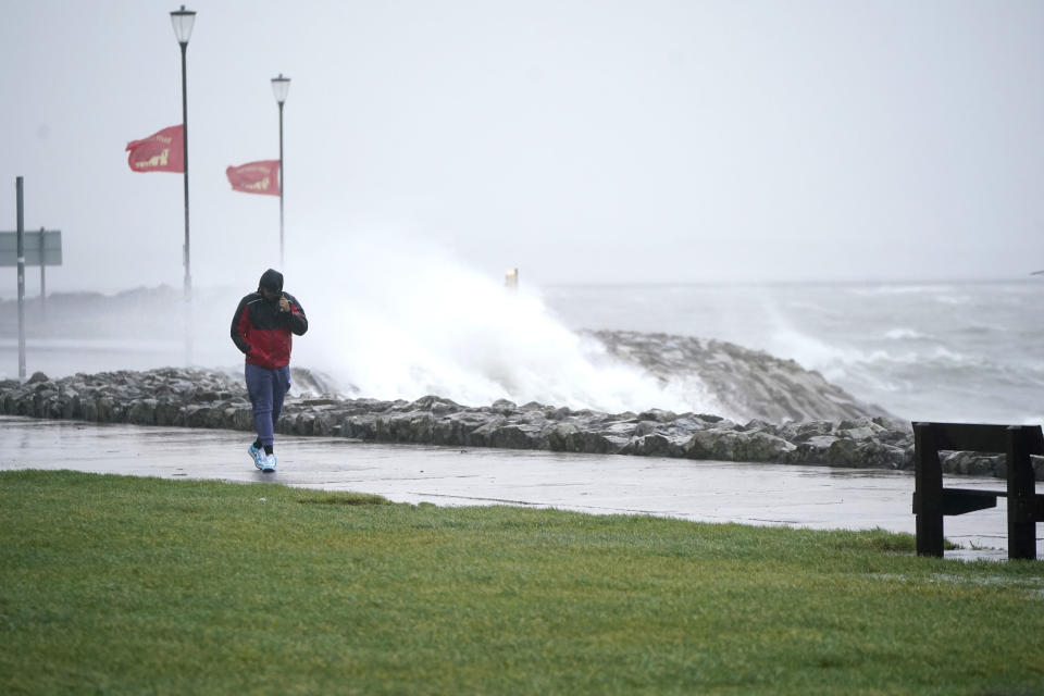 A person walks past high waves in Salthill, Galway, Ireland, Sunday, Jan. 21, 2024, during Storm Isha. (Niall Carson/PA via AP)