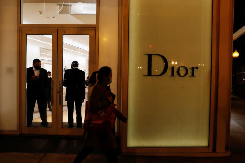 Security guards wear protective face masks as the global outbreak of the coronavirus disease (COVID-19) continues, while a woman walks by a Dior fashion store in Chicago