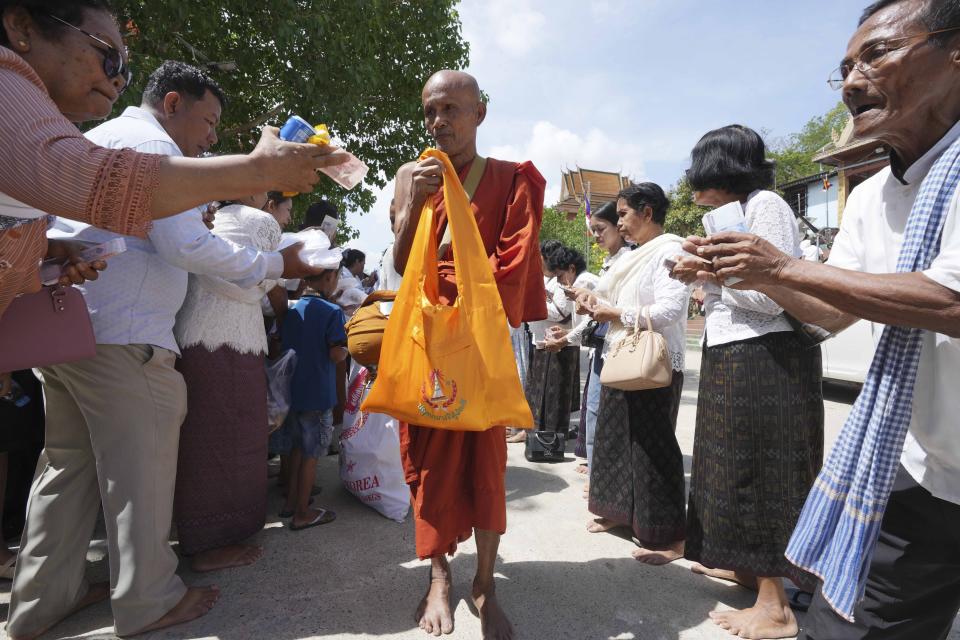 A Buddhist monk receives alms from devotees during the Buddhist Visak Bochea at Praseth Leu pagoda in northwest of Phnom Penh, Cambodia, Wednesday, May 22, 2024. (AP Photo/Heng Sinith)