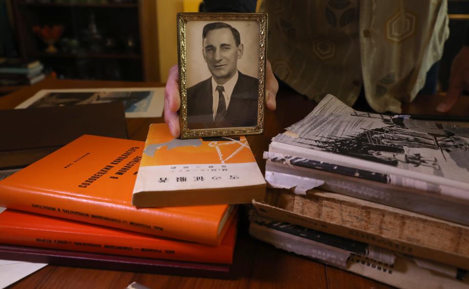 Nick Rozanov holds a photo of his father, Michael Rozanov, at his home in Penfield. The books under the photo were all written by Michael Rozanov, and told of his time served in an internment camp in Siberia.