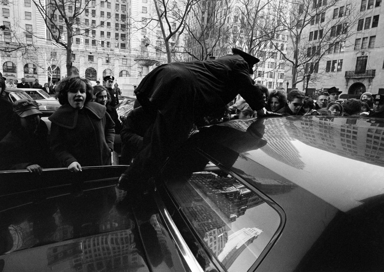 The Beatles' limo driver climbs over the top of his car to get in. It took nine police officers to clear a path for the car to leave