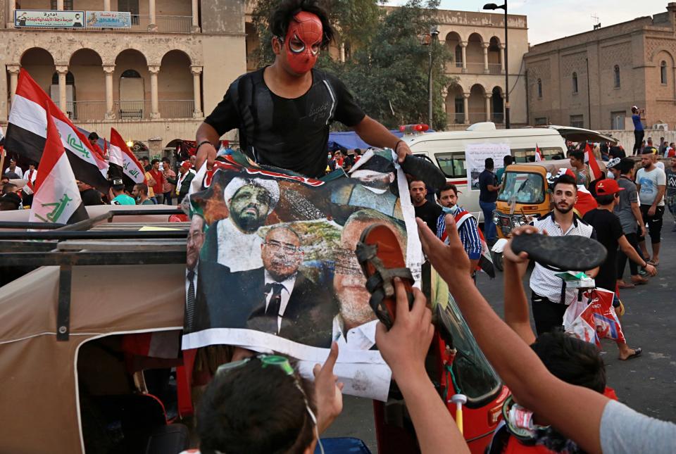 Protesters hit a poster showing Iraqi politicians and militia leaders with a shoe, during ongoing anti-government protests in Baghdad, Iraq, Sunday, Nov. 3, 2019. (AP Photo)