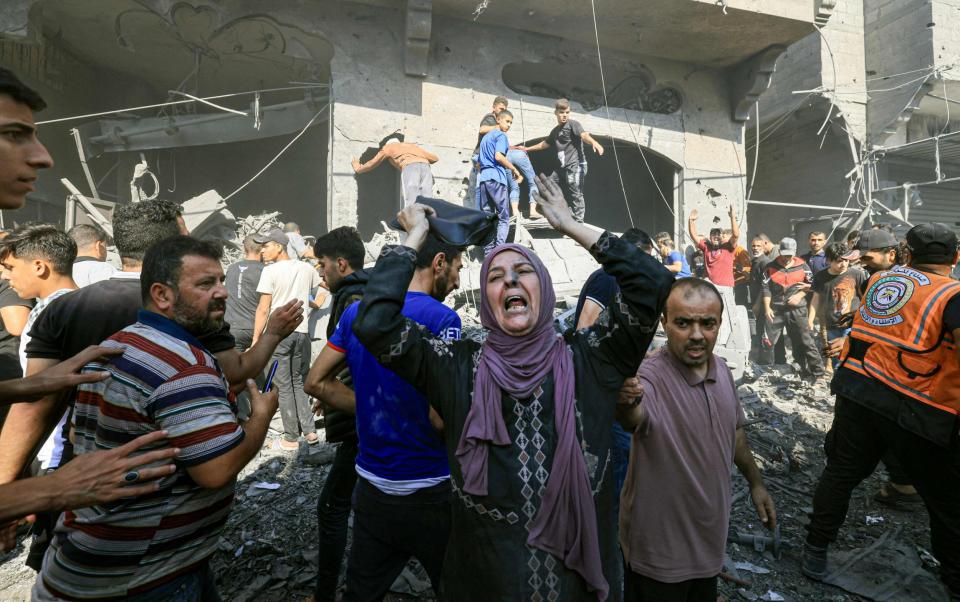 Palestinian people rush to look for victims in the rubble of a building following a strike in Khan Yunis in the southern Gaza Strip