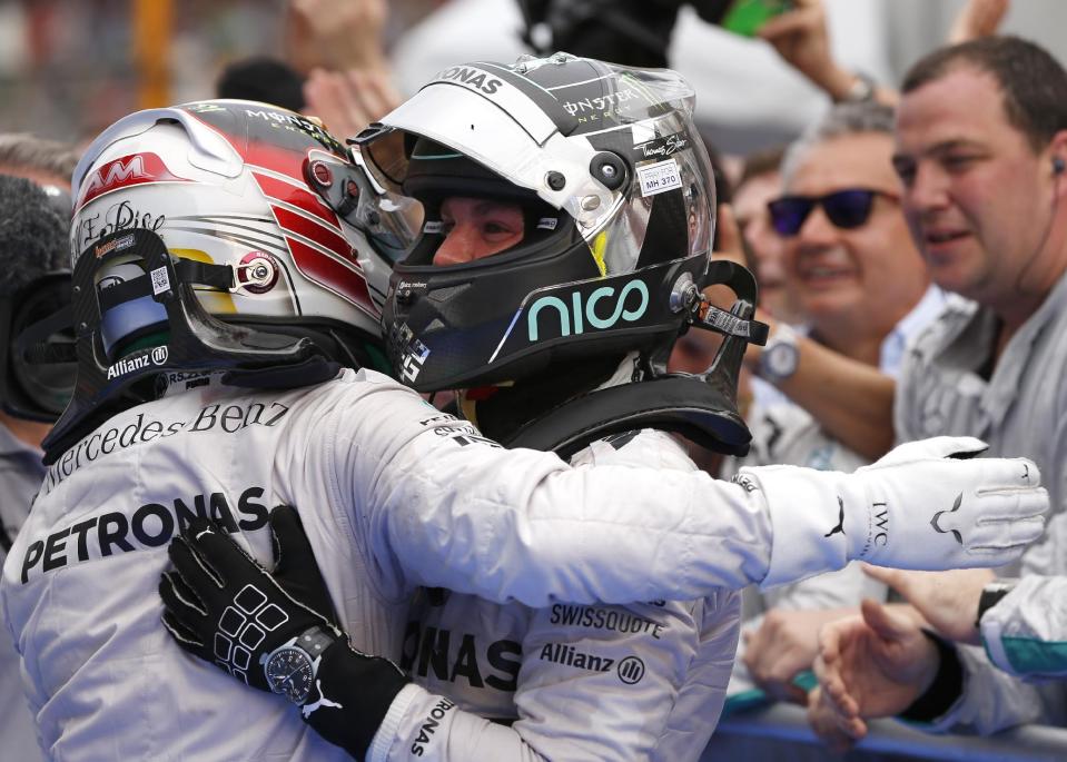 Mercedes driver Lewis Hamilton, left, of Britain is congratulated by teammate and second placed Nico Rosberg of Germany after winning the Malaysian Formula One Grand Prix at Sepang International Circuit in Sepang, Malaysia, Sunday, March 30, 2014. (AP Photo/Vincent Thian)