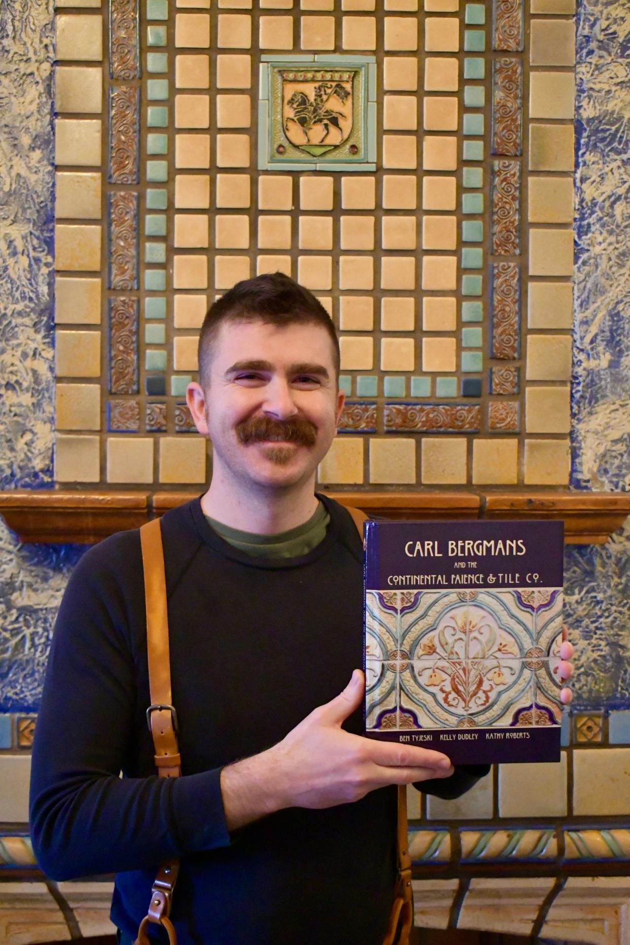 Author Ben Tyjeski is shown with his new book, "Carl Bergmans and the Continental Faience & Tile Co.," next to a fireplace with Continental tiles in Racine.